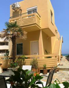 a house with a balcony and a table with plants at Ermis Suites in Platanias