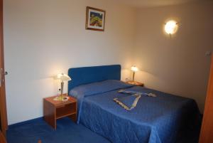 a bedroom with a bed with a blue bedspread and two lamps at Italia Hotel in Nesebar