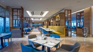 グルガオンにあるHoliday Inn Gurugram Sector 90 by IHGの白いテーブルと青い椅子が備わるレストラン
