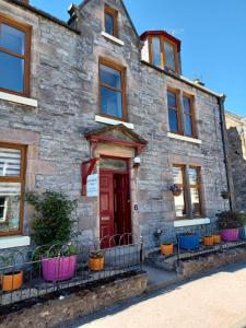 an old stone house with a red door at Gowanbrae Bed and Breakfast in Dufftown