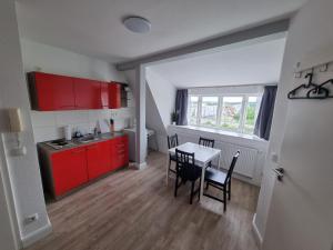 a kitchen with red cabinets and a table and chairs at Nikolai Appartements in Rostock