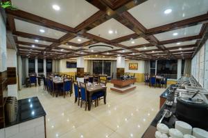 une grande salle à manger avec des tables et des chaises dans l'établissement Abhilashi Residency & Spa - Centrally Heated & Air Cooled, à Manali