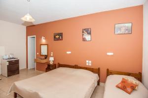 two beds in a bedroom with an orange wall at Folies in Lourdata