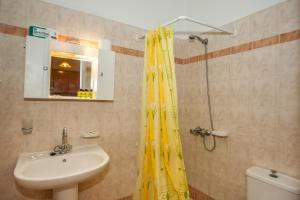 a bathroom with a yellow shower curtain and a sink at Folies in Lourdata
