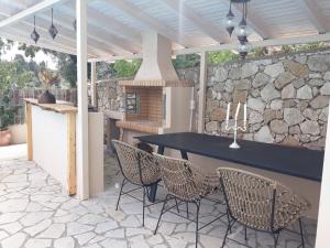a patio with a table and chairs and a stone wall at My Lefkada Boutique Villa by Olga Lounge Hotel - Panoramic View - VISIT THE REAL PARADISE !!! in Lygia