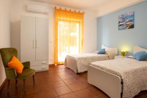 1 dormitorio con 2 camas, silla y ventana en siciliacasevacanze - Villa Venere, en Marina di Ragusa