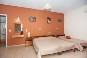 two beds in a bedroom with an orange wall at Folies in Lourdata