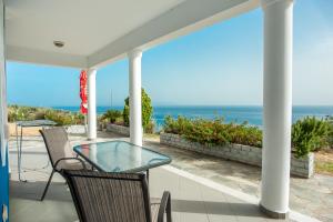 a patio with a table and chairs and the ocean at Folies in Lourdata