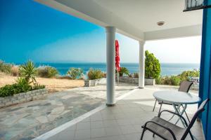 a patio with a table and chairs and the ocean at Folies in Lourdata