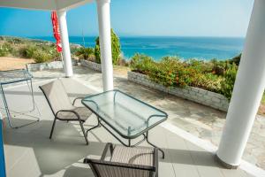 a patio with a table and chairs and the ocean at Folies in Lourdata