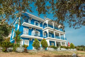 un bâtiment bleu et blanc avec des arbres devant lui dans l'établissement Folies, à Lourdhata