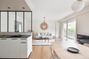 a white kitchen with a table and a living room at L'Eden - Appartement familial au pied du Thabor in Rennes