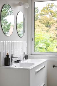 a bathroom with a sink and two mirrors at L'Eden - Appartement familial au pied du Thabor in Rennes