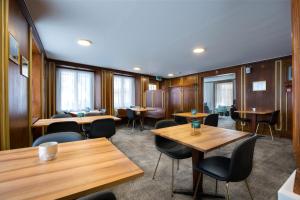 een restaurant met houten tafels, stoelen en ramen bij Krone by b-smart in Bad Ragaz