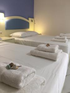 three white beds with towels on top of them at Augusta Methoni Hotel in Methoni