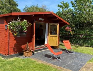 duas cadeiras laranja sentadas em frente a um pequeno barracão em Primrose Cabin em Dorchester