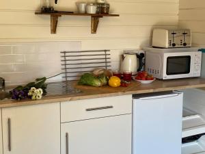 a kitchen with a counter with a microwave and vegetables at Primrose Cabin in Dorchester