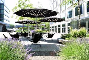 a group of chairs and umbrellas in front of a building at Placid Hotel Design & Lifestyle Zurich in Zürich