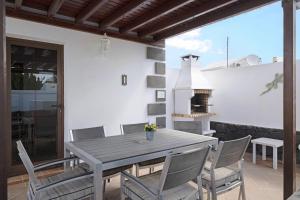 Una mesa y sillas en un patio con chimenea. en Casa Elian, en Playa Blanca