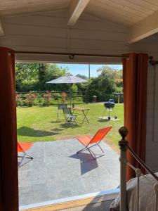 eine Terrasse mit Stühlen, einem Tisch und einem Sonnenschirm in der Unterkunft Primrose Cabin in Dorchester