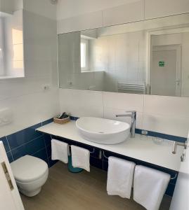 een badkamer met een wastafel, een toilet en een spiegel bij Apartments Kaldana in Rab