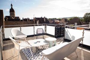 a balcony with chairs and tables on a roof at Les Terrasses de Notre Dame in Beaune