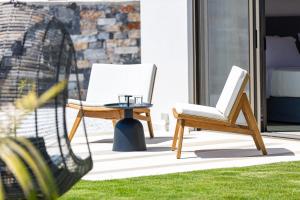 taras z dwoma krzesłami i stołem w obiekcie Terrazzo Luxury Villas w mieście Pigianos Kampos +37 zdjęć