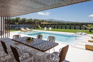 patio ze stołem i krzesłami przy basenie w obiekcie Terrazzo Luxury Villas w mieście Pigianos Kampos