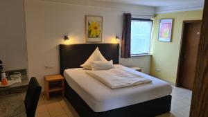 ein kleines Schlafzimmer mit einem Bett mit weißer Bettwäsche und einem Fenster in der Unterkunft Business Pension Gasper in Raunheim