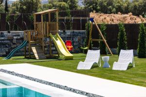 dwa krzesła i plac zabaw przy basenie w obiekcie Terrazzo Luxury Villas w mieście Pigianos Kampos