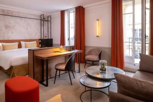 une chambre d'hôtel avec un lit, une table et des chaises dans l'établissement Victoria Palace Hotel, à Paris