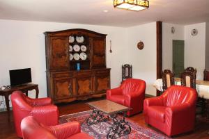 una sala de estar con sillas rojas y un armario de madera. en Domaine De Syam - Gîtes, Chambres d'hôtes & Cabanes en Syam
