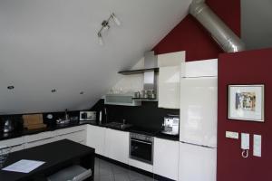 eine Küche mit weißen Schränken und einer roten Wand in der Unterkunft Zweit-Traumwohnung in Marburg an der Lahn