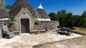 a stone building with a table and a picnic table at Trullo Scrascia. in Ceglie Messapica