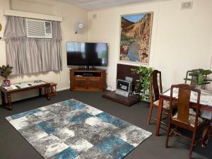 a living room with a flat screen tv and a table at Homely Cottage in Hawker