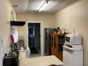 a kitchen with a white refrigerator and a microwave at Homely Cottage in Hawker