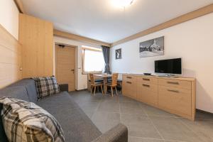 a living room with a couch and a tv at San Martino Mountain Residence in San Martino di Castrozza