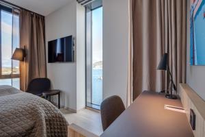a hotel room with a bed and a desk and a window at Quality Hotel Ramsalt in Bodø