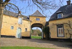 un grand bâtiment jaune avec une arche dans l'établissement B&B Cense de la Tour, à Nil Saint-Vincent