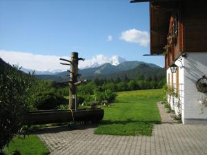 a cross next to a building with mountains in the background at Bognerlehen in Bischofswiesen