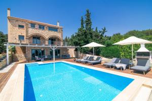Una piscina con sillas y sombrillas al lado de una casa. en Mira Agua Villa, en Vasilikos