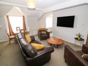 a living room with leather furniture and a flat screen tv at Medical Hall in Cemaes Bay