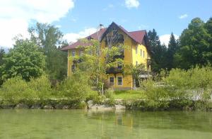 una casa gialla seduta accanto a un corpo d'acqua di Ferienwohnung Engleitner - DorfResort Mitterbach a Mitterbach