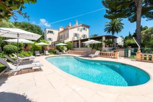 a pool with chairs and umbrellas next to a house at Mas Djoliba in Antibes
