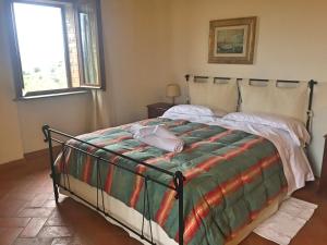 Un dormitorio con una cama grande con una manta verde y colorida en Agriturismo Podere Marcampo, en Volterra