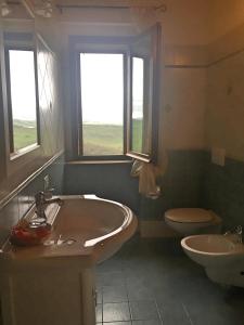 a bathroom with a tub and a toilet and two windows at Agriturismo Podere Marcampo in Volterra