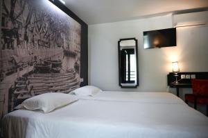a bedroom with a white bed with a picture on the wall at Hôtel Les Muses in Annecy