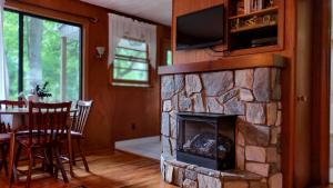 a living room with a stone fireplace with a television at Cozy Creek Cottages in Maggie Valley