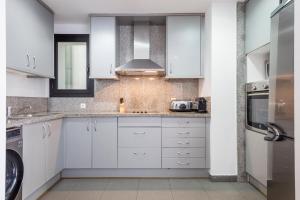 una cocina blanca con armarios blancos y fregadero en Habitat Apartments Carders, en Barcelona