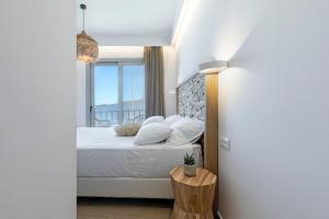 ein Schlafzimmer mit einem Bett und einem großen Fenster in der Unterkunft Boho Sapiens Marina - Cinnamon Era, Adamas Port in Adamas